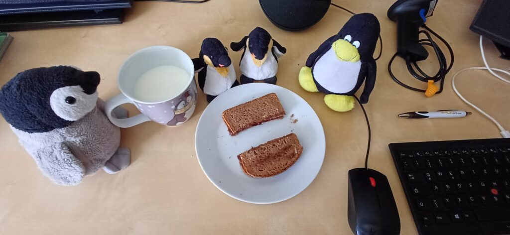 Foto mit Pinguinen, und Frühstpck bestehend aus einer Tasse Milch und einem zweigeteilten Nutellabrot