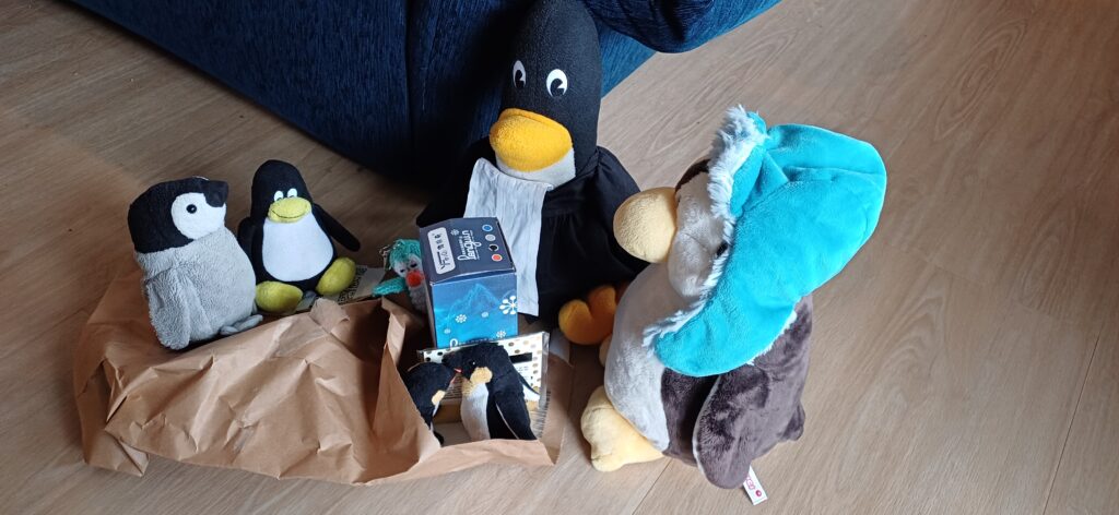 Nicki, Pinguin im Talar, Mütux, Fred, Georg und Neville packen das Paket aus.